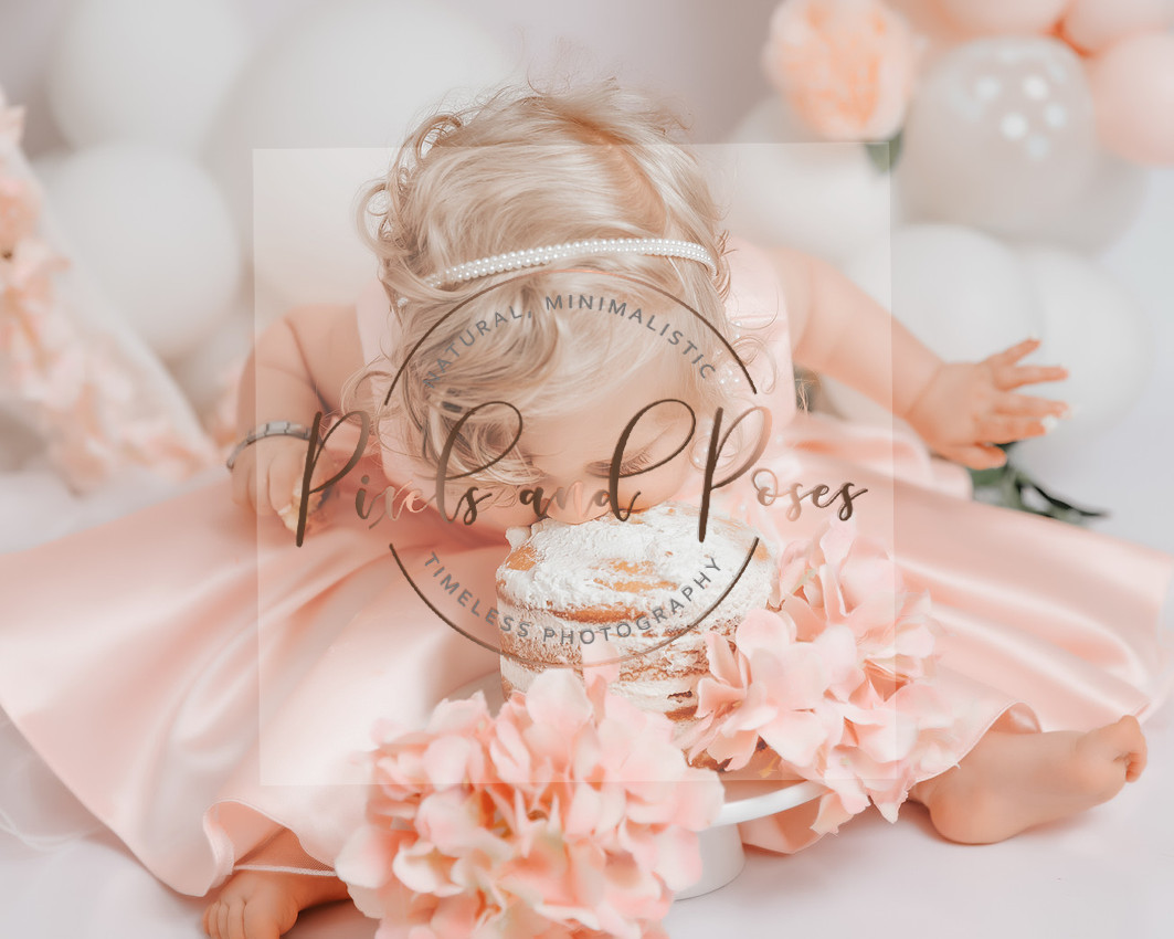 Baby eating her birthday cake during sweet peonies and eucalyptus cake smash session in Derbyshire studio